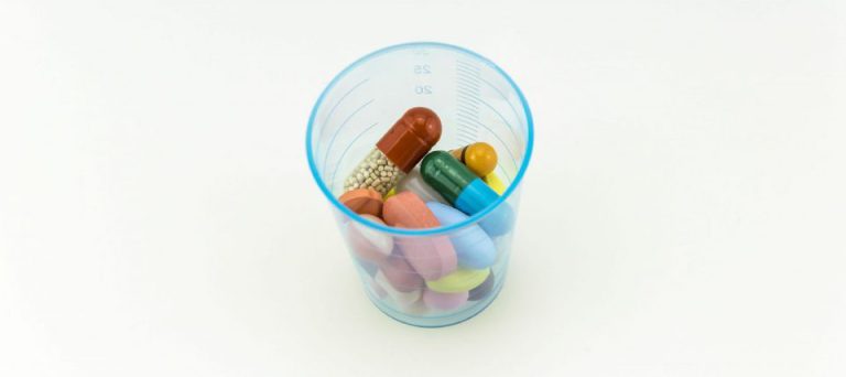 A small cup filled with assorted pills and capsules