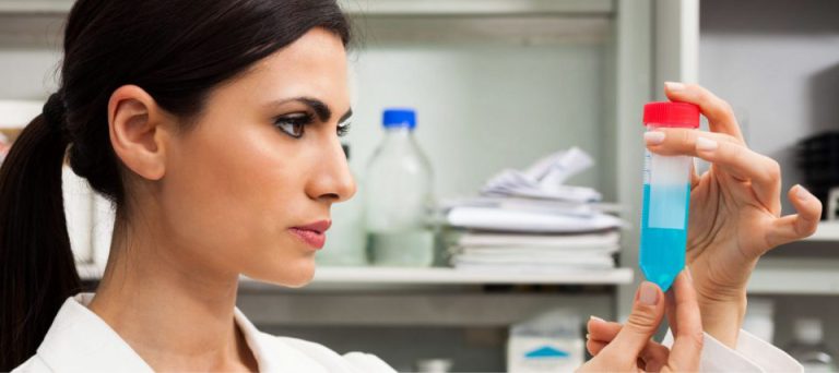 A researcher in a lab coat holding a sample vial