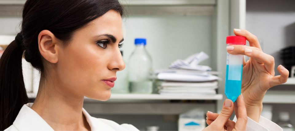 A researcher in a lab coat holding a sample vial