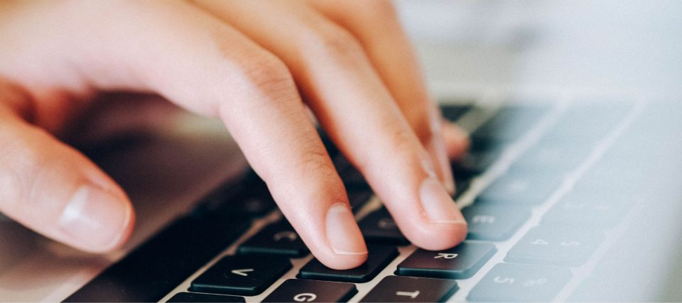 Close-up of hands typing on a laptop keyboard