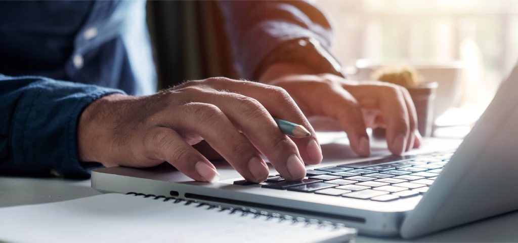 Hands typing on a laptop keyboard at a desk