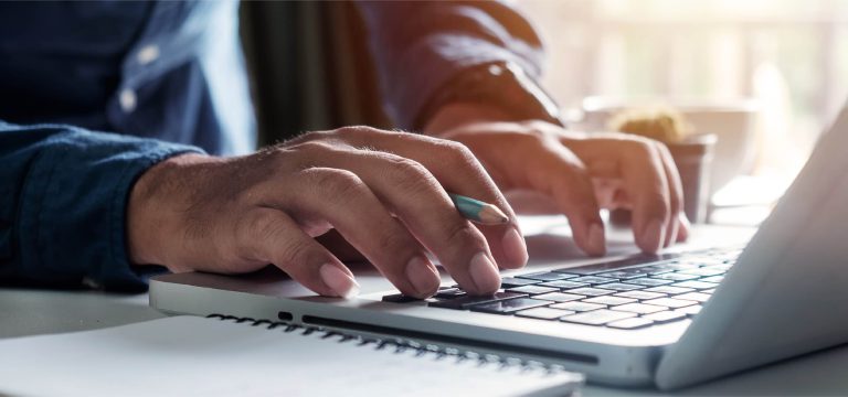 Hands typing on a laptop keyboard at a desk
